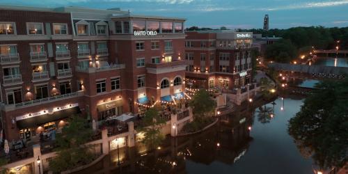 Riverside buildings at dusk with lit pathways and reflections on the water.